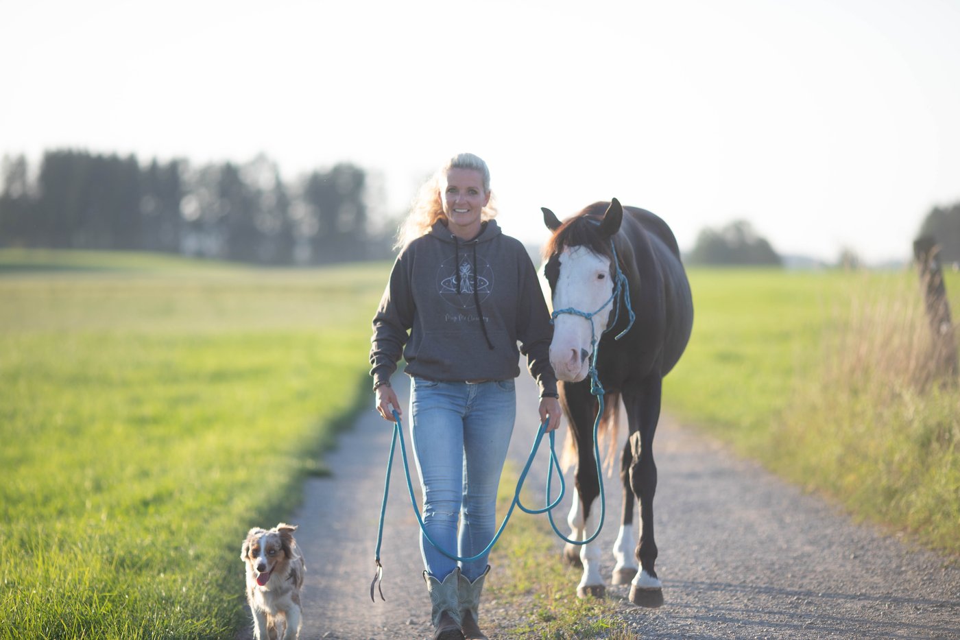 Caro geht mit ihrem Pferd und dem Hund einen Feldweg entlang