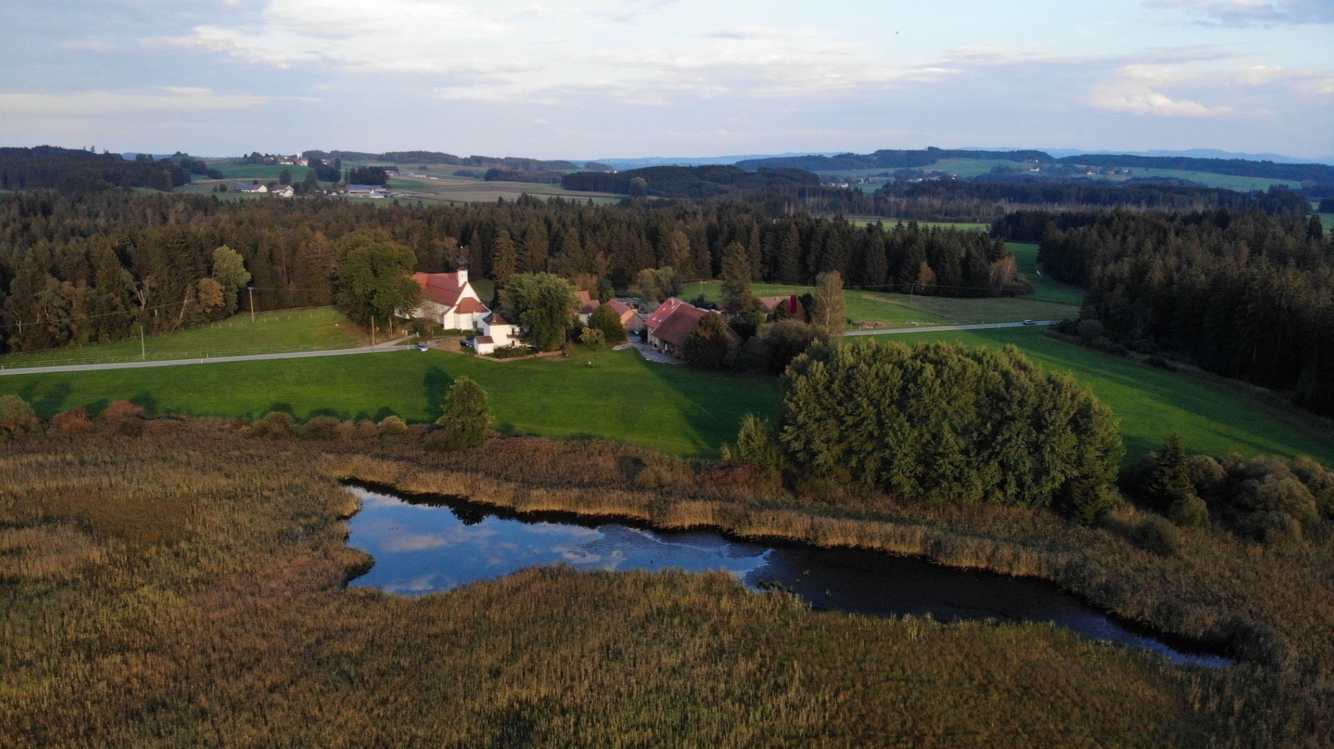 Luftbild der Landschaft rund um die Ranch mit Weiher, Wiesen und Wäldern